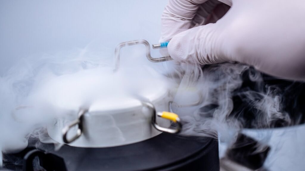 Laboratory professional handling cryogenic storage equipment for biologic material preservation at Cross Biologics